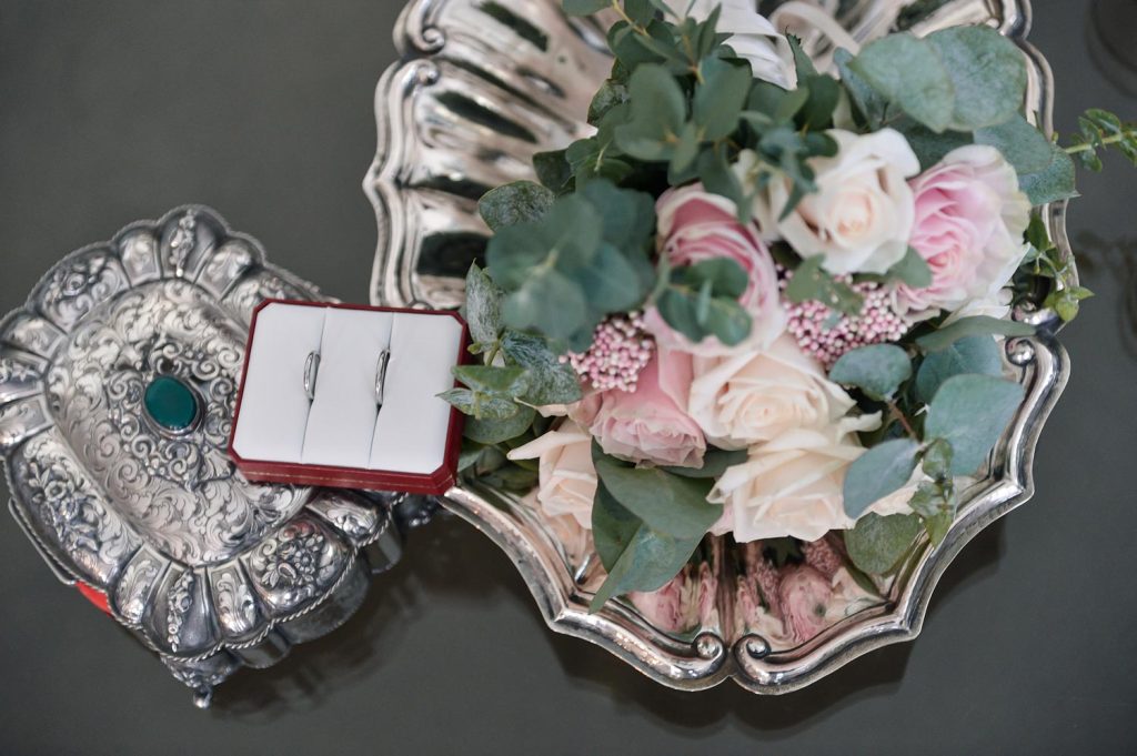 Dettagli matrimonio in Villa del ‘600 in Valtellina con anelli nuziali e bouquet su vassoio antico