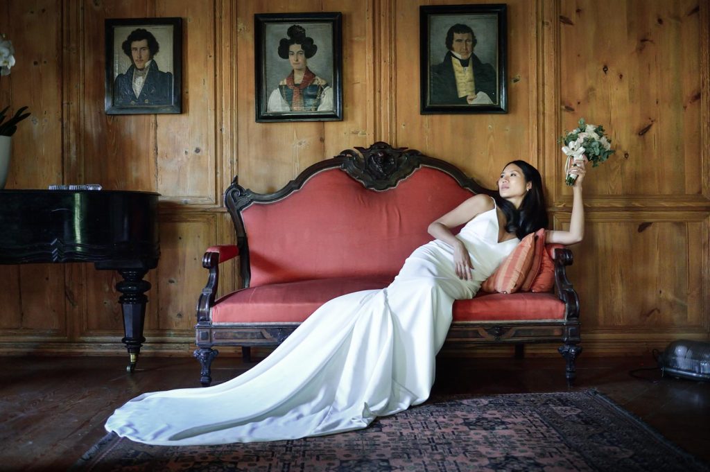 Sposa in abito bianco nella Villa del ‘600 in Valtellina sdraiata sul divano storico durante il servizio fotografico