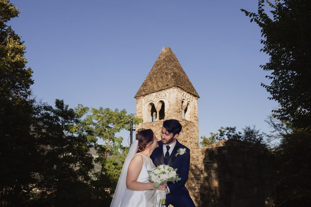 Sposi abbracciati davanti a torre medievale durante servizio fotografico di matrimonio in Valtellina