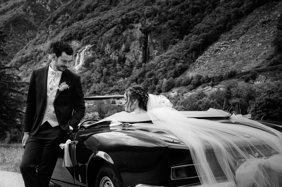 Sposi accanto all’auto dopo la cerimonia di matrimonio a Chiavenna